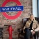 A lady sitting in a chair with thew Whitehall logo on a wall behind her