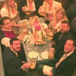 A group of Whitehall staff sitting a t a table holding up drinks