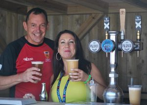 Two people holding drinks behind a bar